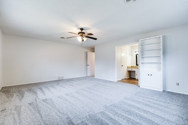 unfurnished bedroom with ceiling fan, a textured ceiling, light colored carpet, and ensuite bathroom