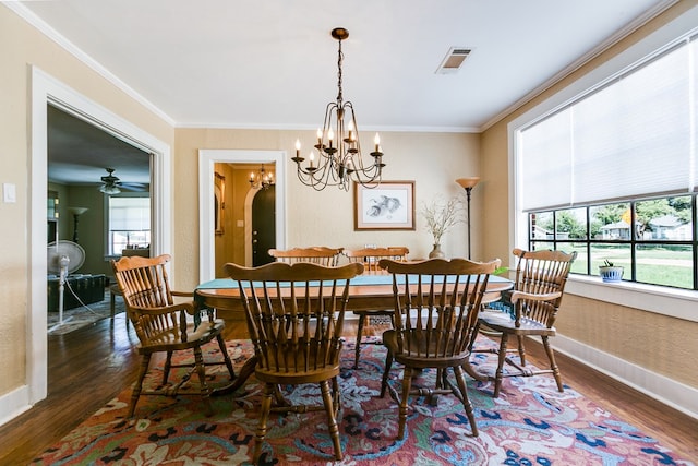 dining area featuring dark wood-type flooring, ornamental molding, and a chandelier