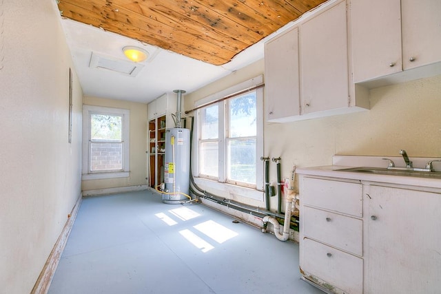 interior space with water heater, white cabinetry, plenty of natural light, and sink