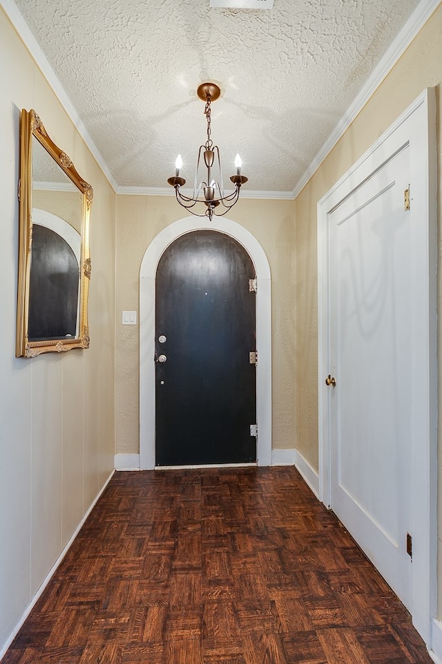 entrance foyer with ornamental molding, a chandelier, a textured ceiling, and dark parquet floors