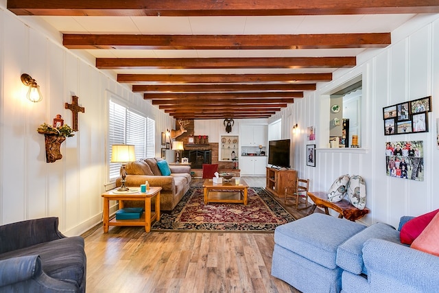 living room featuring beamed ceiling and light hardwood / wood-style flooring