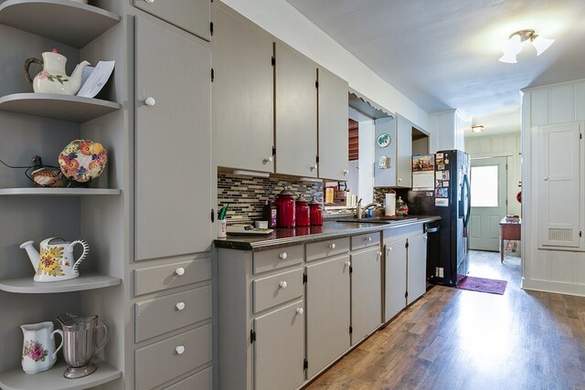 kitchen with tasteful backsplash, sink, hardwood / wood-style flooring, and black refrigerator with ice dispenser