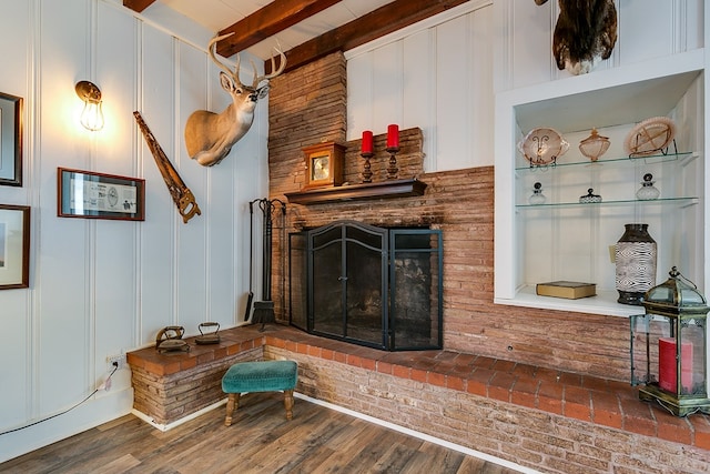 living room featuring hardwood / wood-style floors, beamed ceiling, and a brick fireplace