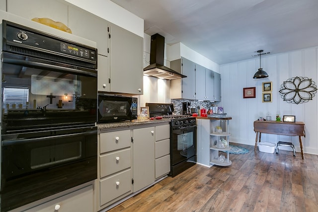 kitchen with decorative light fixtures, backsplash, black appliances, dark wood-type flooring, and wall chimney exhaust hood