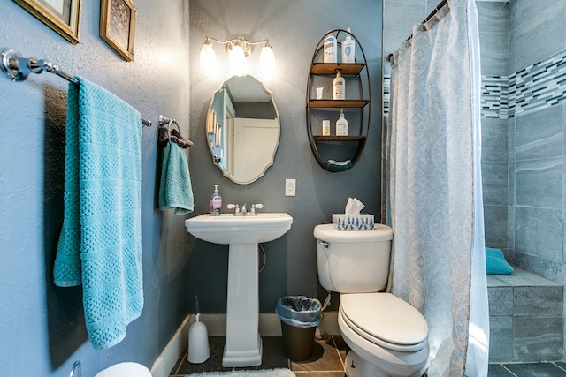 bathroom with toilet, curtained shower, and tile patterned flooring