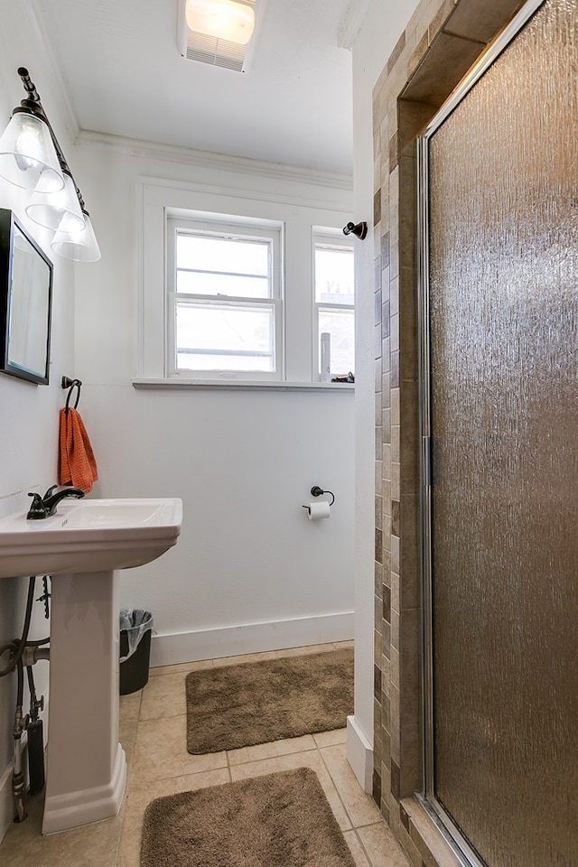 bathroom with tile patterned flooring, a shower with shower door, and ornamental molding