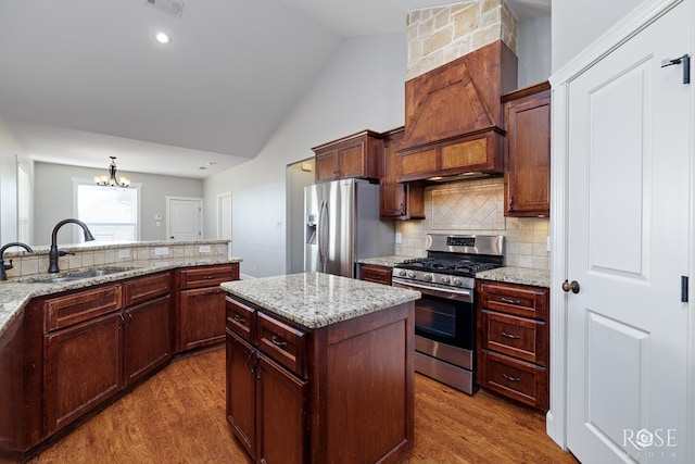 kitchen with sink, appliances with stainless steel finishes, a center island, light stone countertops, and custom exhaust hood