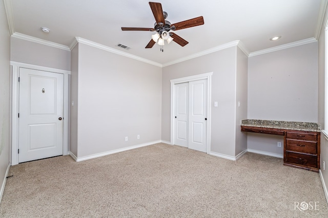 unfurnished bedroom featuring ornamental molding, light carpet, built in desk, and ceiling fan