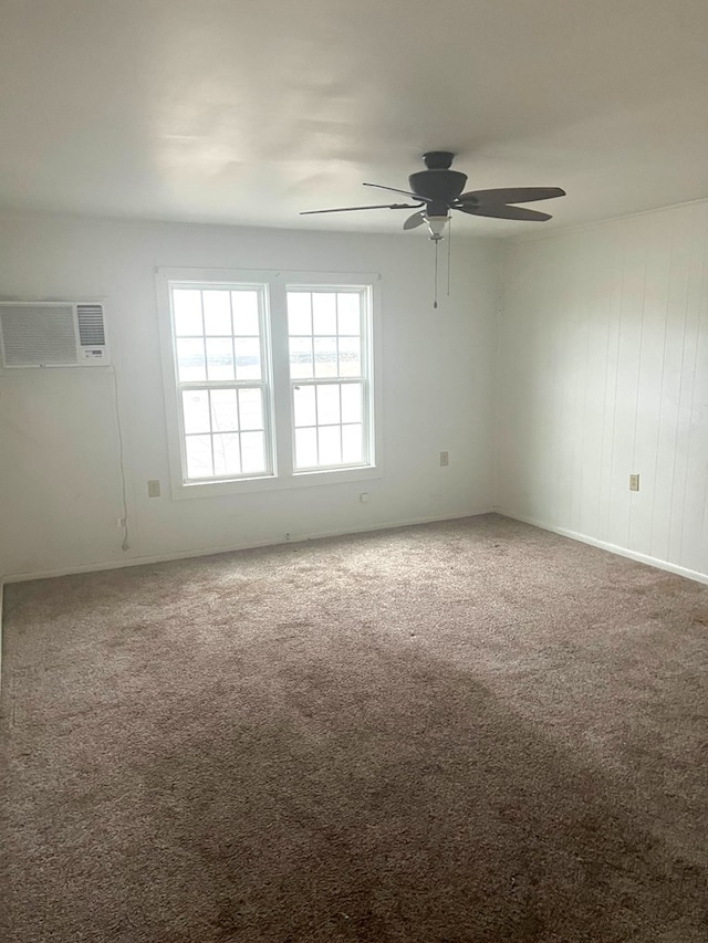 spare room with carpet flooring, a wall mounted AC, and ceiling fan