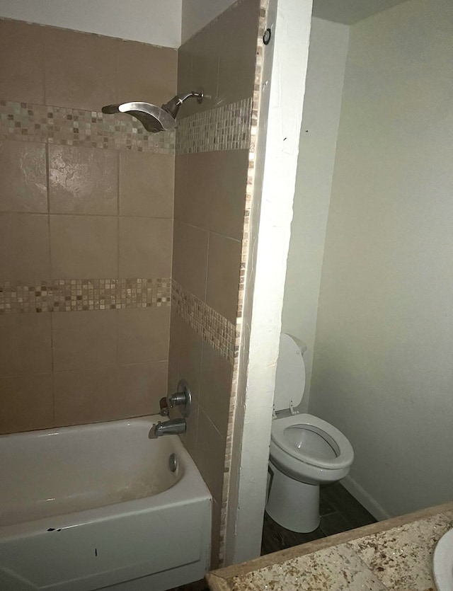 bathroom featuring tiled shower / bath and toilet