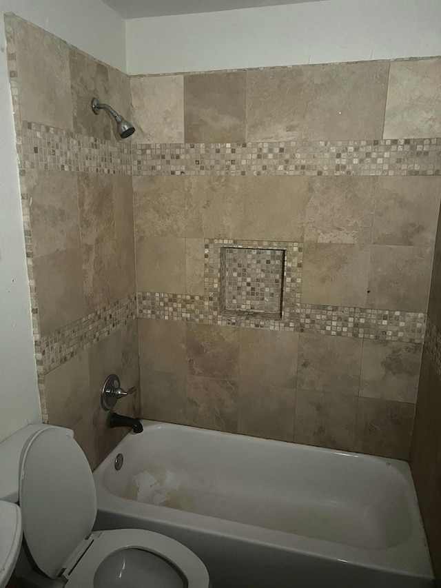 bathroom with toilet and tiled shower / bath combo