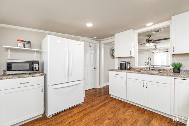 kitchen featuring visible vents, white cabinets, stainless steel microwave, freestanding refrigerator, and a sink