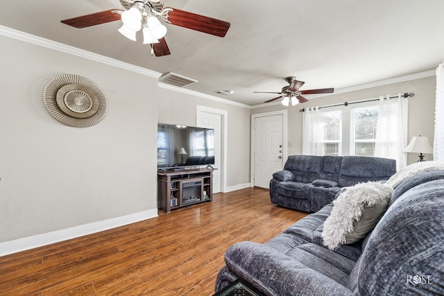 living room featuring a textured ceiling, ornamental molding, wood finished floors, and visible vents