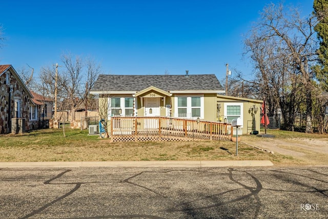 bungalow-style home featuring a front lawn, roof with shingles, a wooden deck, and central air condition unit