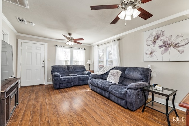 living area featuring ornamental molding, dark wood-style flooring, visible vents, and baseboards