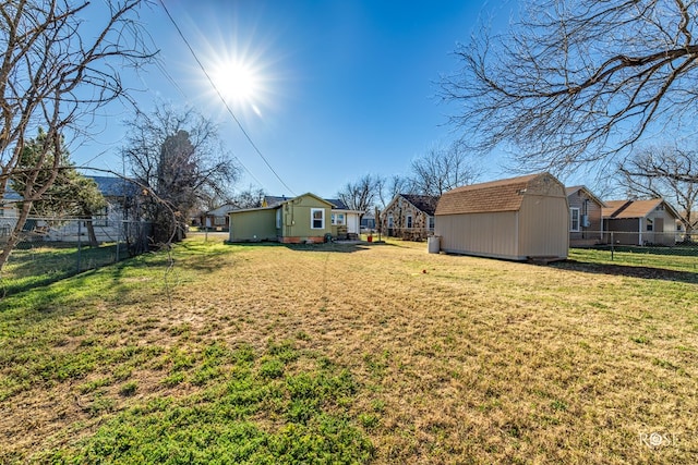 view of yard with a storage unit, a residential view, fence, and an outbuilding