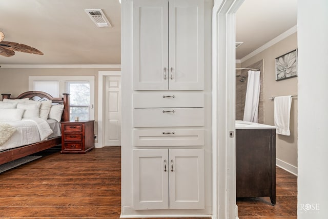 bedroom featuring baseboards, dark wood finished floors, visible vents, and crown molding