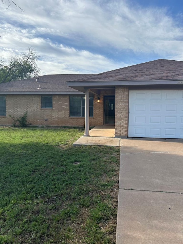 single story home featuring a garage and a front lawn