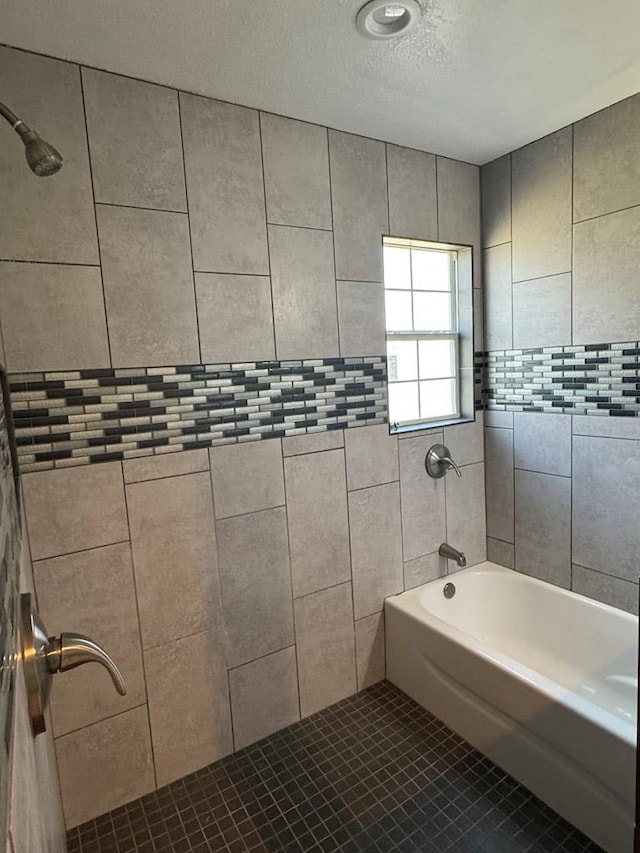 bathroom featuring tiled shower / bath combo, tile patterned floors, and a textured ceiling