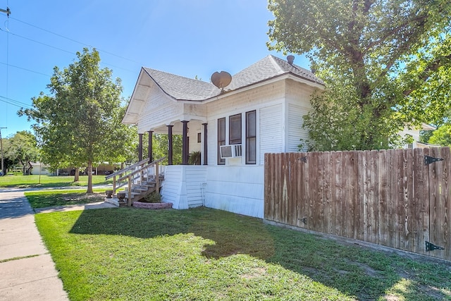 view of side of home featuring cooling unit, covered porch, and a lawn