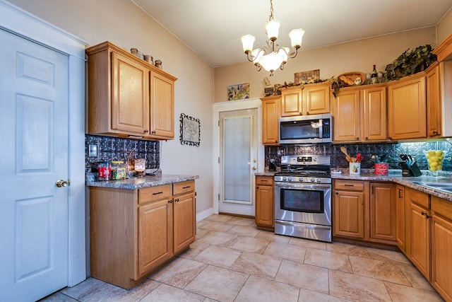 kitchen with appliances with stainless steel finishes, pendant lighting, tasteful backsplash, a chandelier, and light stone counters