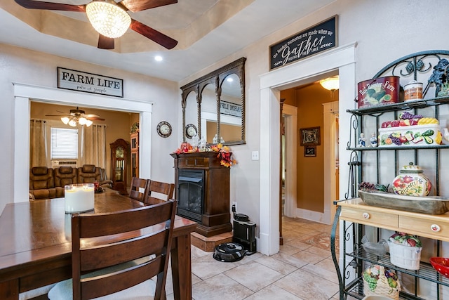 tiled dining area with a raised ceiling and ceiling fan