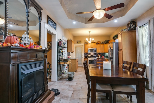 dining space featuring a tray ceiling and ceiling fan with notable chandelier