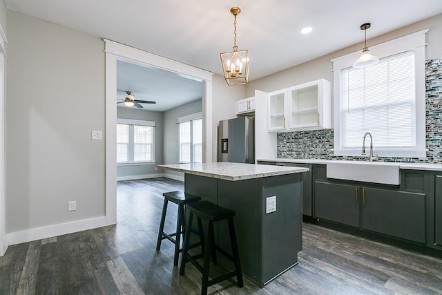 kitchen featuring hanging light fixtures, stainless steel fridge, white cabinets, and a kitchen island