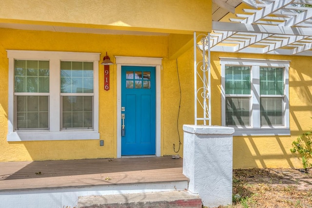 view of exterior entry with a pergola