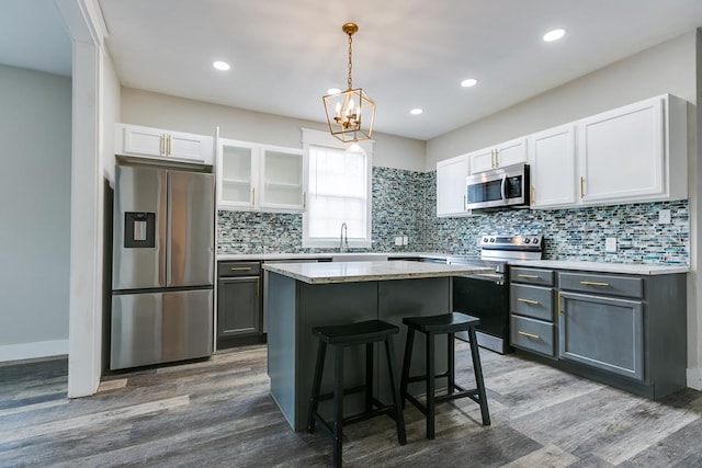 kitchen featuring gray cabinets, appliances with stainless steel finishes, white cabinetry, a kitchen island, and decorative light fixtures