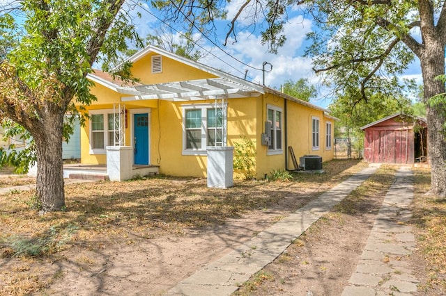 bungalow-style house with central AC, a storage unit, and a pergola