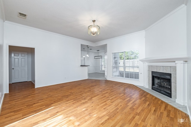 unfurnished living room with a tiled fireplace, a textured ceiling, and light hardwood / wood-style flooring