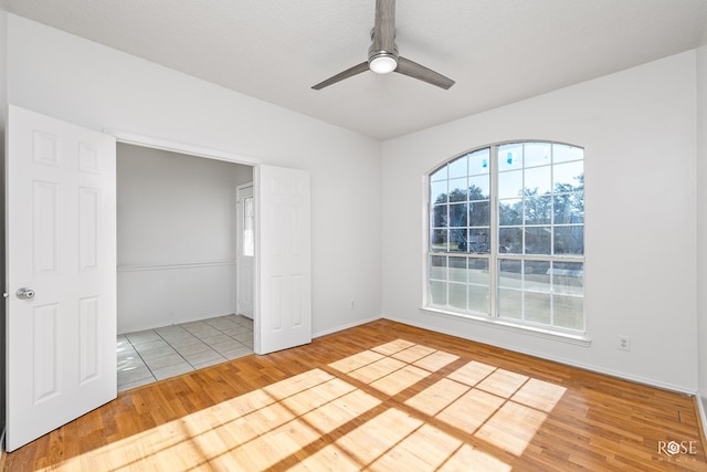 empty room with ceiling fan, wood-type flooring, and a healthy amount of sunlight