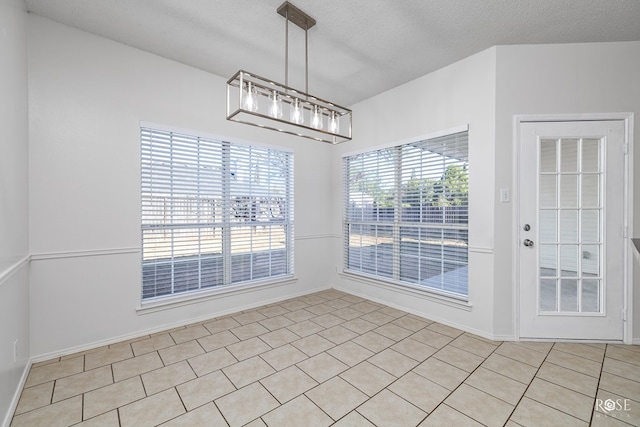 unfurnished dining area featuring light tile patterned floors and a textured ceiling