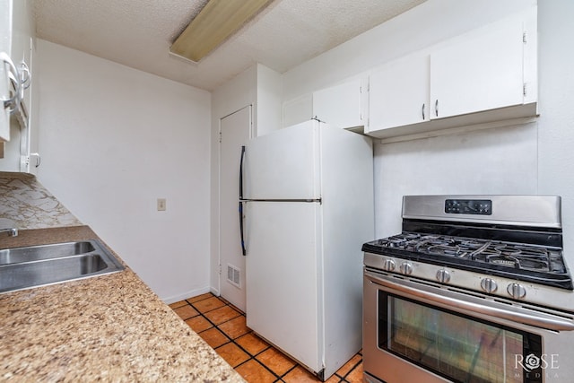 323 E 6th St, San Angelo, TX 76903 - kitchen with stainless steel range with gas stovetop, freestanding refrigerator, a sink, white cabinetry, and light countertops