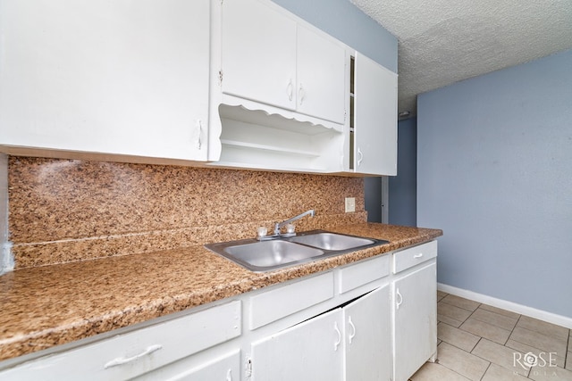 323 E 6th St, San Angelo, TX 76903 - kitchen featuring a sink, decorative backsplash, white cabinetry, light tile patterned floors, and baseboards