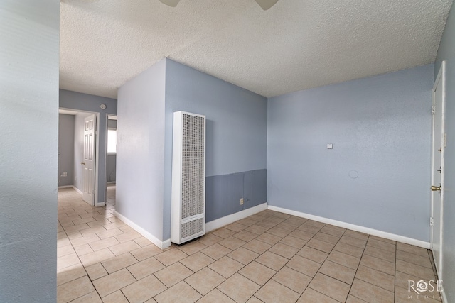 323 E 6th St, San Angelo, TX 76903 - unfurnished room featuring a heating unit, a textured ceiling, tile patterned floors, and baseboards