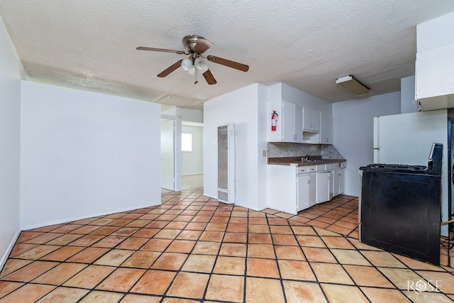323 E 6th St, San Angelo, TX 76903 - kitchen featuring gas range oven, a heating unit, a ceiling fan, white cabinets, and backsplash