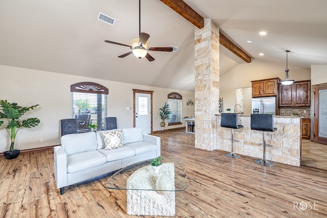 7738 Bison Trl, San Angelo, TX 76901 - living room featuring decorative columns, beam ceiling, ceiling fan, light wood finished floors, and high vaulted ceiling