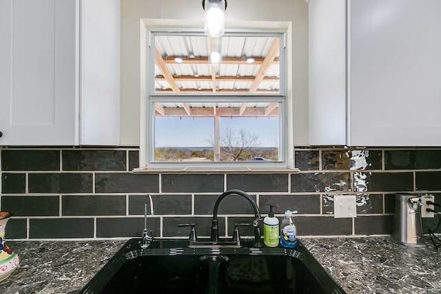 kitchen featuring a sink, decorative backsplash, dark stone countertops, and white cabinetry