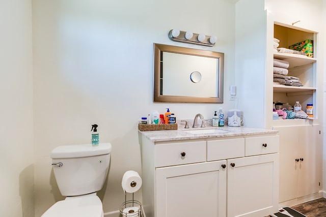 bathroom featuring toilet, vanity, and baseboards