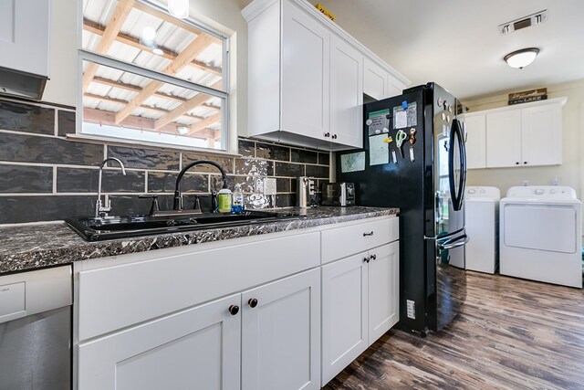 kitchen with washer and clothes dryer, a sink, white cabinets, dark wood-style flooring, and visible vents