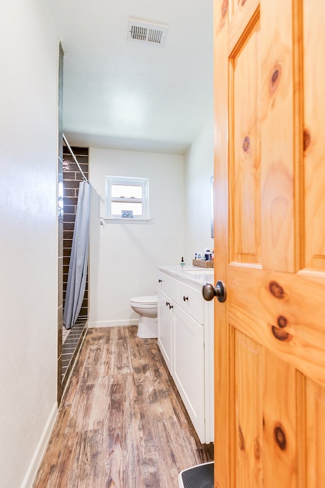 bathroom featuring wood finished floors, visible vents, baseboards, curtained shower, and toilet