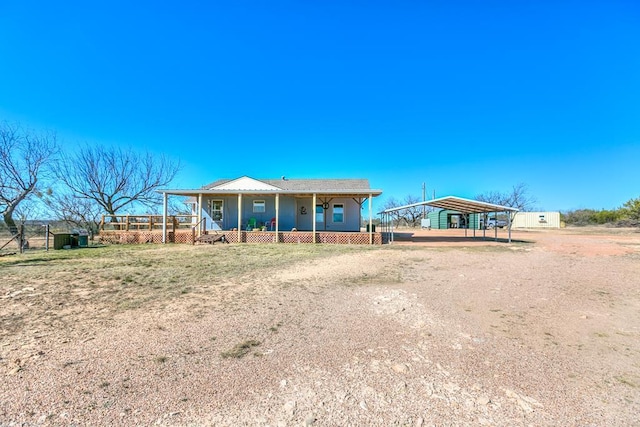 view of front of property featuring a carport, covered porch, and dirt driveway