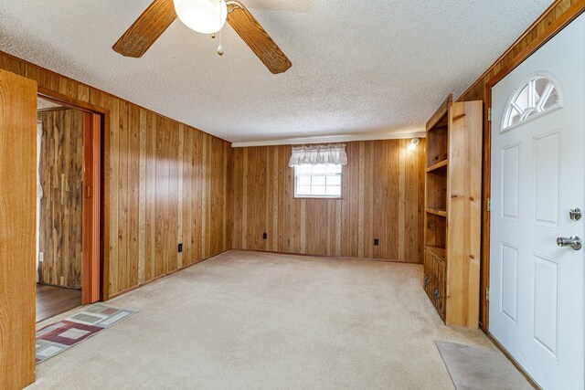 8881 Rust Rd, San Angelo, TX 76905 - foyer entrance featuring wooden walls, a textured ceiling, light carpet, and ceiling fan