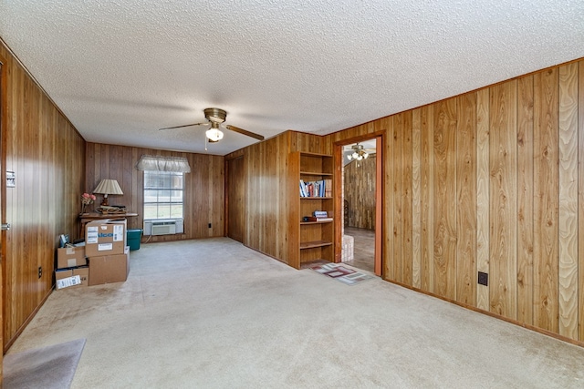 8881 Rust Rd, San Angelo, TX 76905 - unfurnished living room featuring a ceiling fan, wooden walls, carpet, a textured ceiling, and cooling unit