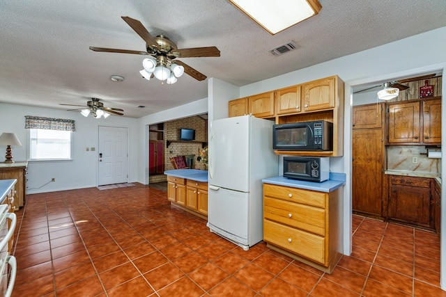 8881 Rust Rd, San Angelo, TX 76905 - kitchen featuring freestanding refrigerator, black microwave, dark tile patterned flooring, a textured ceiling, and a ceiling fan