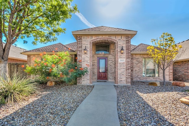 entrance to property with brick siding and fence