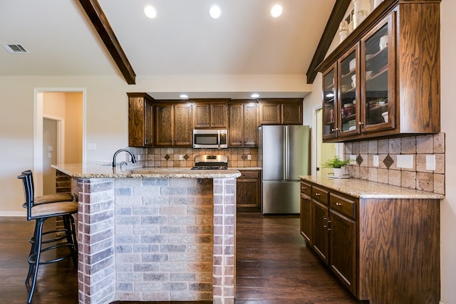 kitchen featuring appliances with stainless steel finishes, dark wood-type flooring, glass insert cabinets, and light stone counters