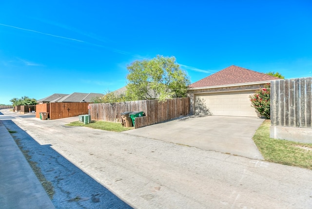 view of front of home featuring a garage, fence private yard, central AC, and roof with shingles